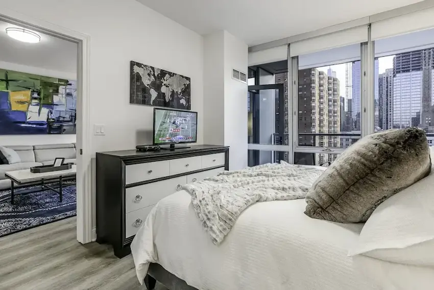 Furnished executive apartment bedroom with floor-to-ceiling windows and downtown Chicago views